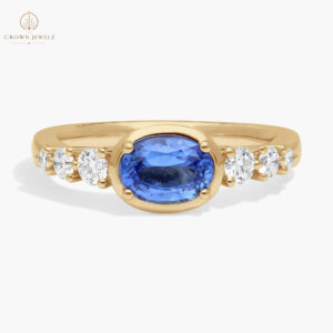 East-West Oval Cut Sapphire Ring With Half Bezel and Diamond Accent In 14K Yellow Gold