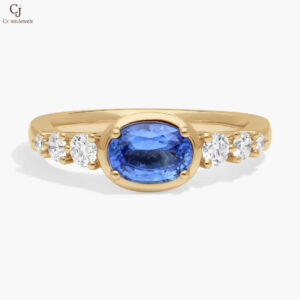 East-West Oval Cut Sapphire Ring With Half Bezel and Diamond Accent In 14K Yellow Gold